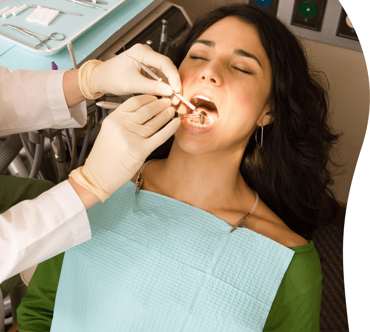 Dentist's hands holding tools examining a woman's mouth