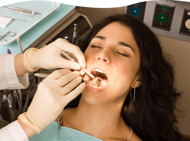 Dentist's hands holding tools examining a woman's mouth